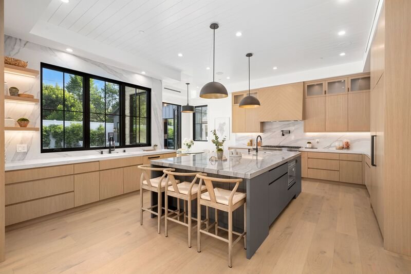 Interior de cocina moderna con una gran isla y gabinetes de madera.